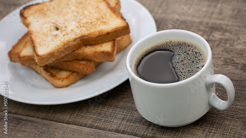 Cup of black coffee and toasted toast on wooden table