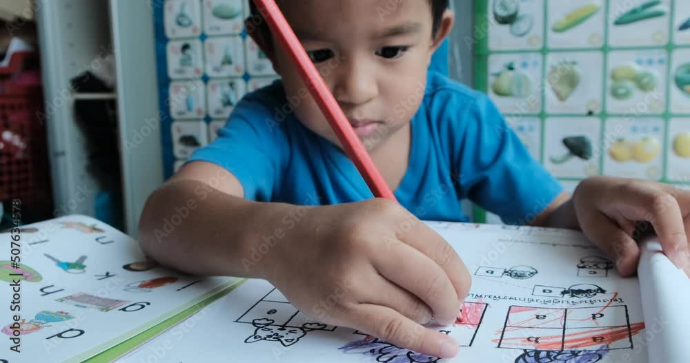 Little kindergarten boy drawing color pencil on paper homework