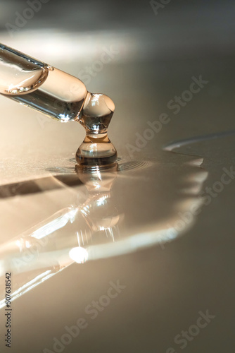 A Dripping Pipette of cosmetic gel on a beige background. photo
