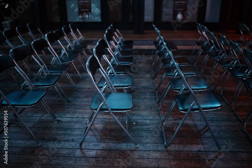 Black folding chairs stand in a dark room, hub