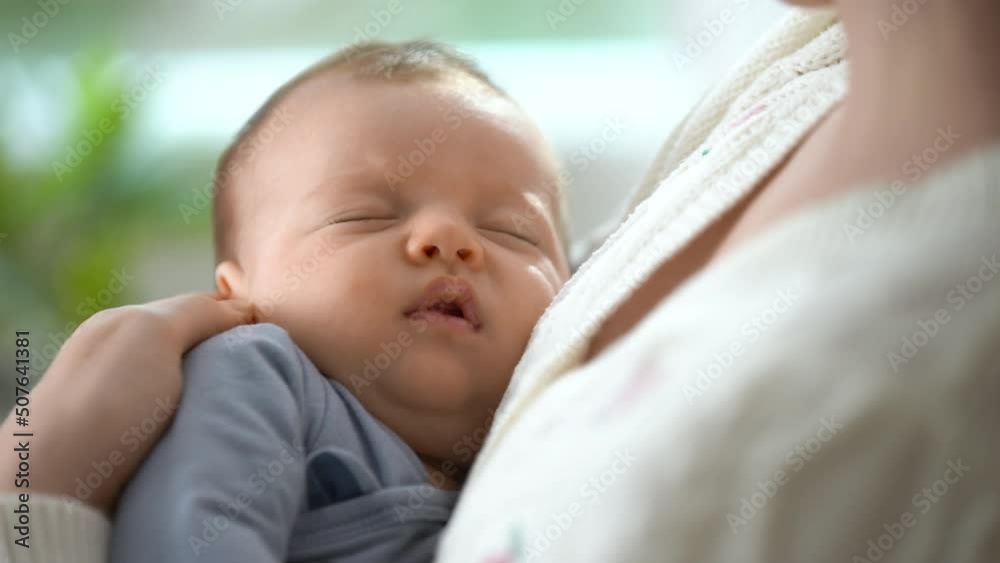 Happy mother holding a sleeping baby in her arms. A loving mother carries her newborn baby at home. Maternity, Parenthood and Motherhood. Beautiful Happy Family. Close-up Happy mother holding a sleeping baby in her arms. A loving mother carries her newborn baby at home. Maternity, Parenthood and Motherhood. Beautiful Happy Family. Close-up