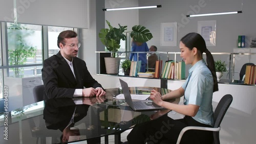 Diverse business partners discuss contract and shake hands in modern office
