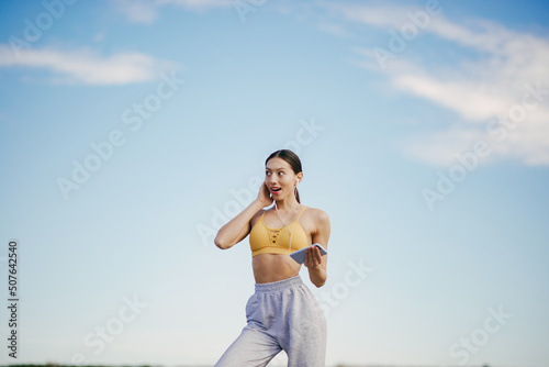 Cute girl with phone training on a sky backgroung photo