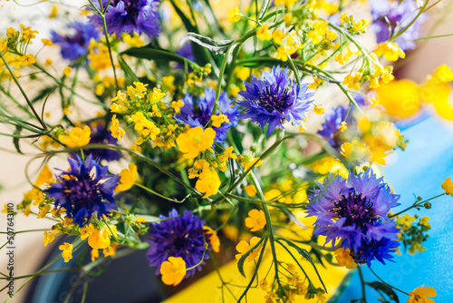 Fototapeta Naklejka Na Ścianę i Meble -  Close up of bouquet of blue and yellow flowers with ukrainian flag. No war in Ukraine. Independence day