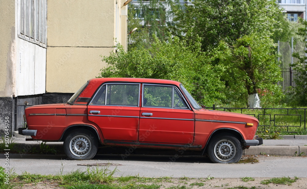 An old red Soviet car in the courtyard of a residential building, Voroshilov Street, St. Petersburg, Russia, May 2022