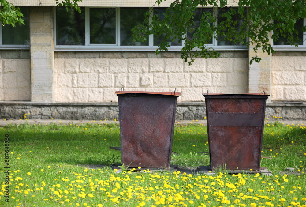 Two rusty metal dumpsters in the yard