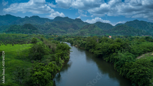 Aerial view landscape with mountains, forest and a river beautiful scenery, Tree lined foliage on both sides of the river flowing through the rural countryside and hills.