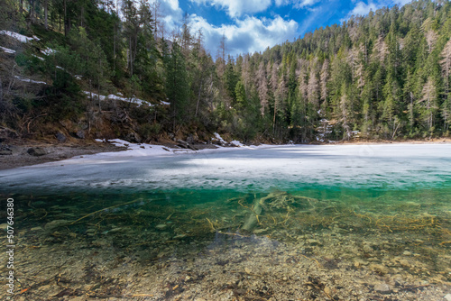 partly frozen, clear mountain lake in the forest during spring (Blindsee, Tyrol, Austria)