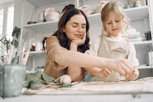 Portrait of mother and little girl shaping clay together
