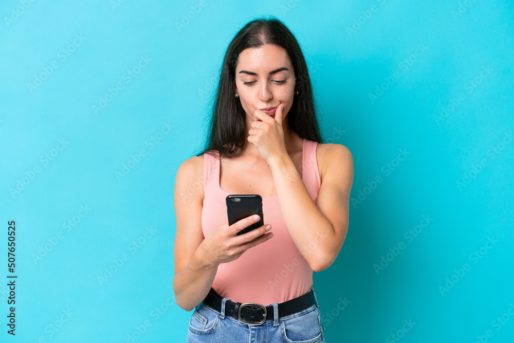 Young caucasian woman isolated on blue background thinking and sending a message Young caucasian woman isolated on blue background thinking and sending a message