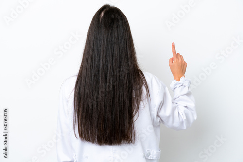 Young caucasian woman isolated on white background wearing a doctor gown and pointing back