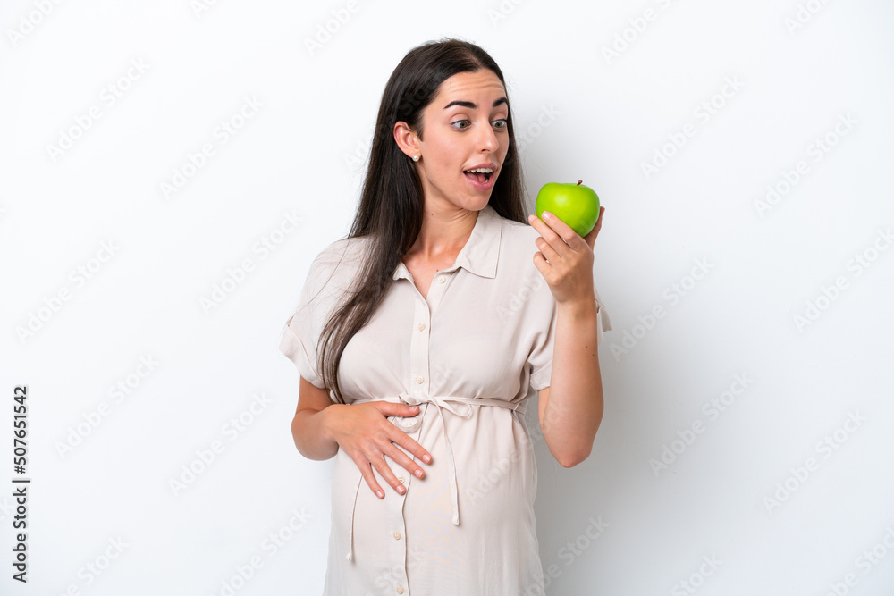 Young caucasian woman isolated on white background pregnant and holding an apple Young caucasian woman isolated on white background pregnant and holding an apple
