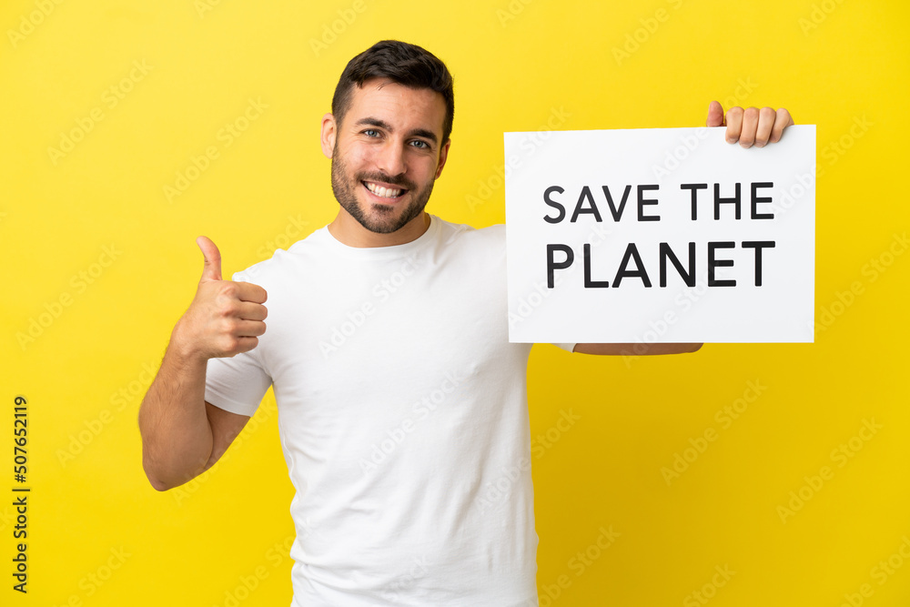 Young handsome caucasian man isolated on yellow background holding a placard with text Save the Planet with thumb up Young handsome caucasian man isolated on yellow background holding a placard with text Save the Planet with thumb up