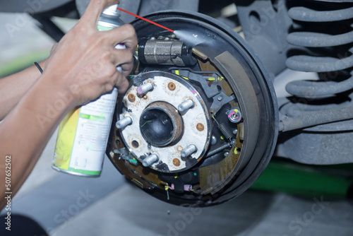Maintenance and repair of cars in the service center. Close-up of the hands of a mechanic performing a brake pad replacement. Return of the brake pad cylinders by means of a depressor. selective focus