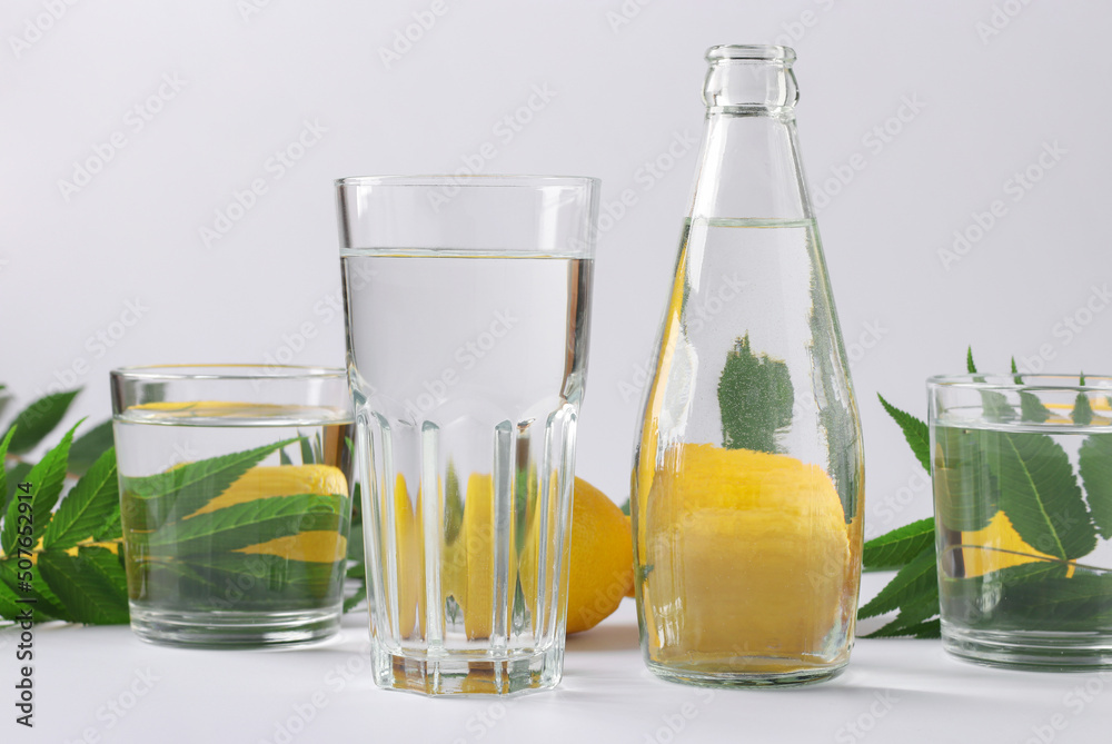 Distortion of an object through transparent vessels filled with water. Distorted lemons and green leaves lie behind glass vessels