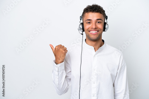 Telemarketer Brazilian man working with a headset isolated on white background pointing to the side to present a product © luismolinero