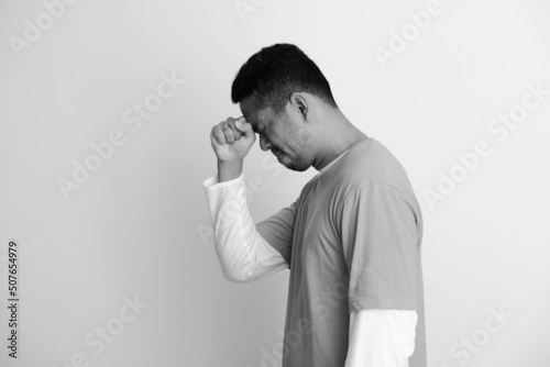 Side view of adult Asian man putting hand on his forehead showing regret expression photo