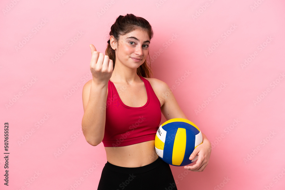 Young caucasian woman playing volleyball isolated on pink background making money gesture