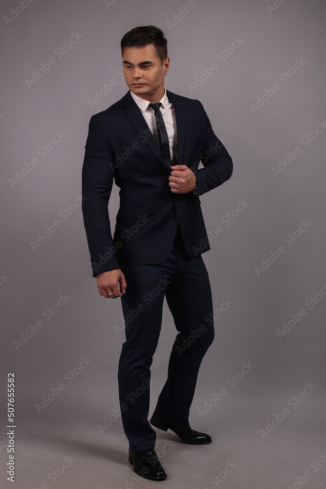 Portrait of a beautiful man guy brunet in the studio in a black classic suit and tie, big strongman Portrait of a beautiful man guy brunet in the studio in a black classic suit and tie, big strongman