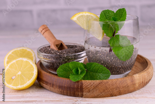 A glass of water with lemon, mint and chia seeds on a wooden tray.Close-up. 