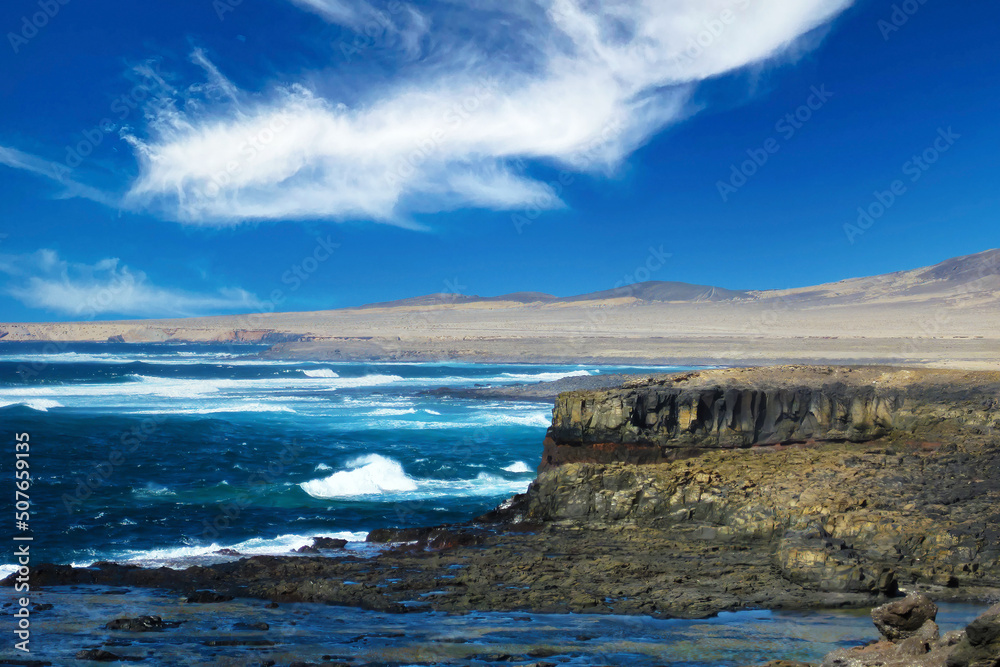 Obraz premium Beautiful lonely wild rough south-east coast, jagged rocks, strong waves, dry arid sand dunes, steep cliffs, clear blue sky - Jandia national Park, Fuerteventura