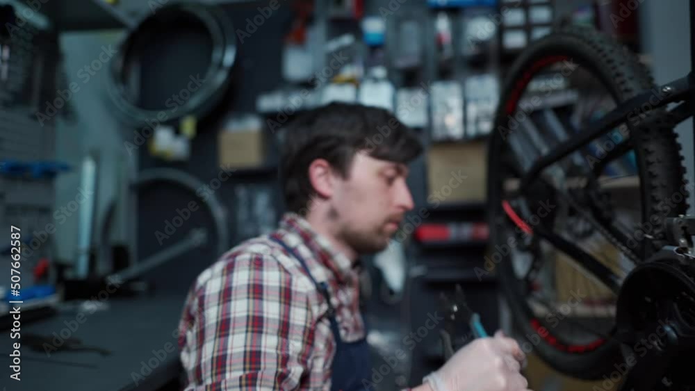 A cycle technician fixes the bicycle chain with a special work tool at the cycling service center. Bicycle mechanic in a workshop in the repair process. Open the bike chain lock A cycle technician fixes the bicycle chain with a special work tool at the cycling service center. Bicycle mechanic in a workshop in the repair process. Open the bike chain lock