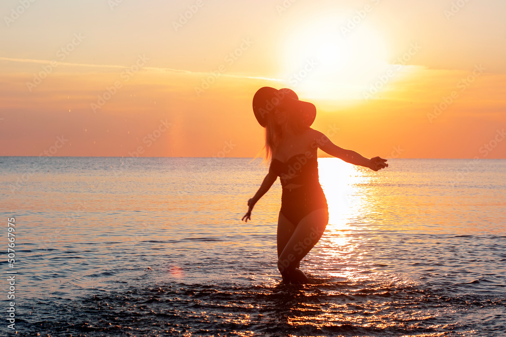 Silhouette of a girl on the sea at sunrise. Vacation and travel concept.