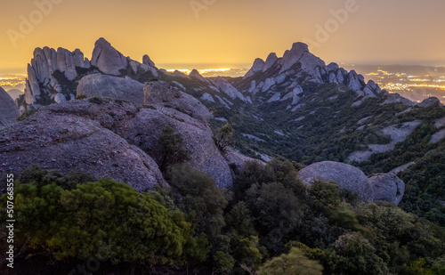 Paisaje de la montaña del parque natural de Montserrat por la noche con las luces de fondo de Barcelona (Cataluña, España).