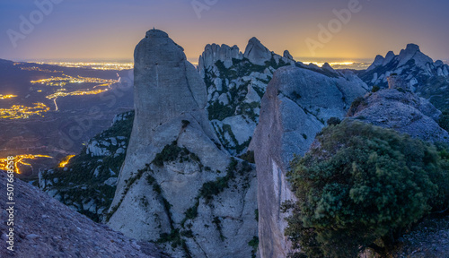Paisaje de la montaña del parque natural de Montserrat por la noche con las luces de fondo de Barcelona (Cataluña, España).