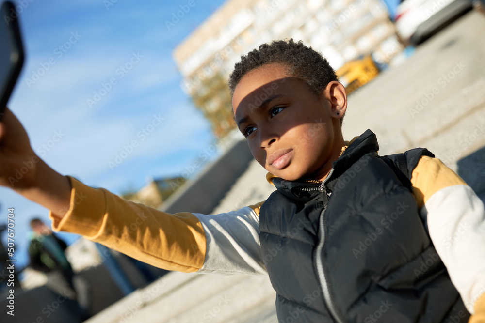 Φωτογραφία Side view of cute adorable beautiful African American boy holding phone and maki