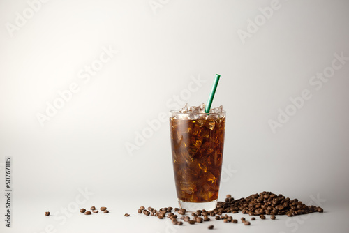 Iced americano coffee with coffee beans on grey background, Glass of black coffee, Beverage at coffee shop. photo