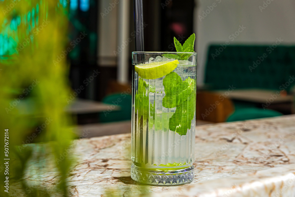 Mojito rum alcoholic cocktail served in a highball glass with ice cubes garnished with lemon and mint at the bar Mojito rum alcoholic cocktail served in a highball glass with ice cubes garnished with lemon and mint at the bar