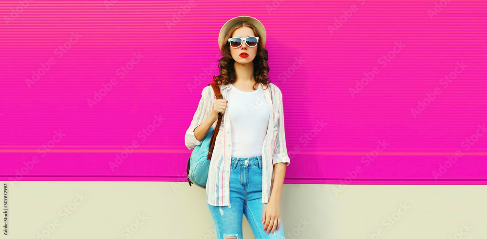 Beautiful young woman posing wearing summer straw hat, backpack on city street on pink background, blank copy space for advertising text Beautiful young woman posing wearing summer straw hat, backpack on city street on pink background, blank copy space for advertising text
