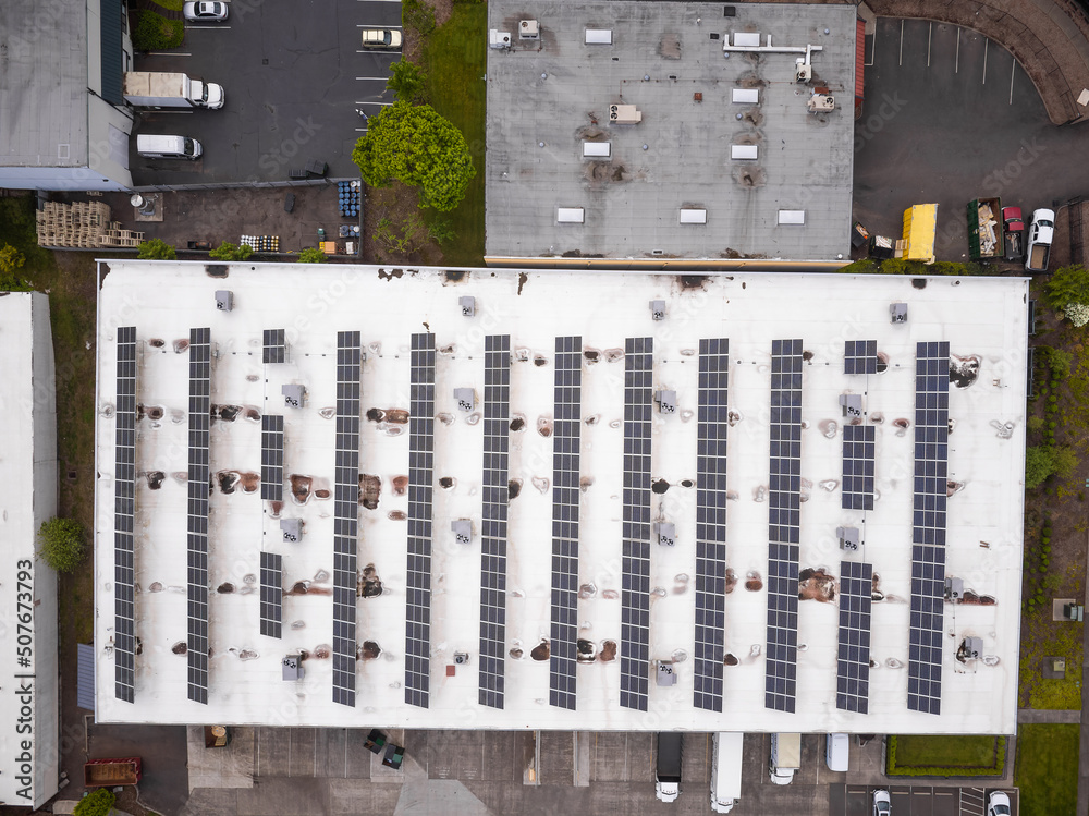 Shooting from a drone. A large roof of an industrial building, parking, a lot of cars on the highway. Green lawns. Map, planning, topography, infrastructure, ecology.