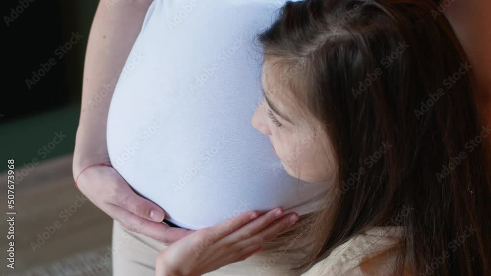 A little girl is stroking her mother's belly while waiting for her little sister.
A little girl is stroking her mother's belly while waiting for her little sister.