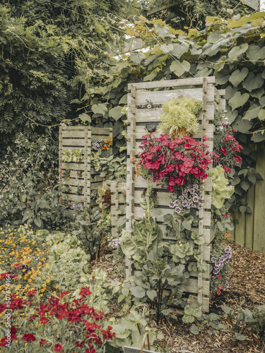 Jolie jardin potager composé de fleurs et de légumes cultivés à la verticale dans des tours en bois photo