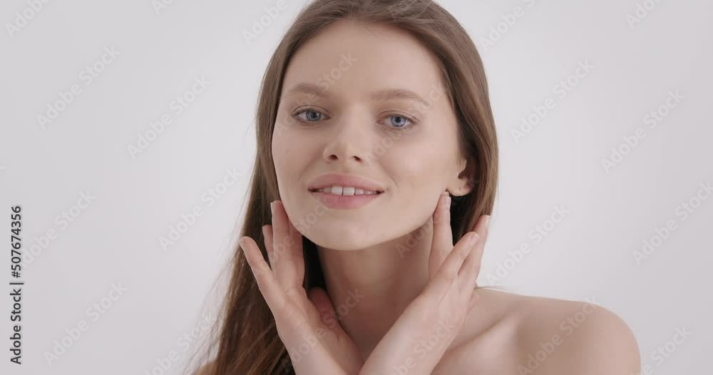 Woman beauty face. Portrait of pretty caucasian woman touching gently her fresh face in studio. Beautiful young model with blue eyes and plump lips isolated over grey background. Woman beauty face. Portrait of pretty caucasian woman touching gently her fresh face in studio. Beautiful young model with blue eyes and plump lips isolated over grey background.