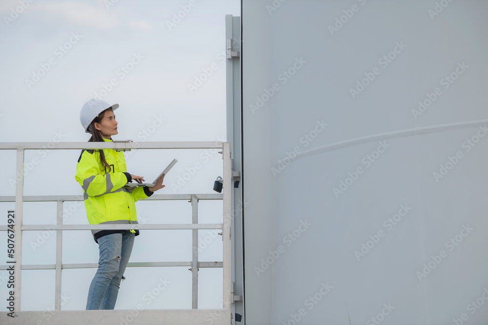 women engineer working and holding the report at wind turbine farm Power Generator Station on mountain,Thailand people women engineer working and holding the report at wind turbine farm Power Generator Station on mountain,Thailand people