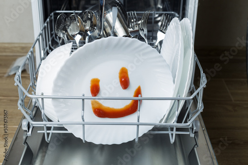 well-washed dishes in the dishwasher. a happy emotion is depicted on a plate