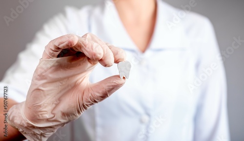 Dentist hand holding white healthy tooth. Implantation, oral hygiene, stomatology, caries and periodontal disease prevention concept. Woman in lab coat and gloves. High quality photo photo