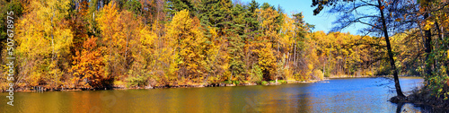 Autumn landscape, panorama, banner - view of lake with reflection in the water of autumn trees against a clear blue sky