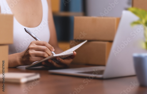 selling products online. A young woman is packing products to send to customers online.