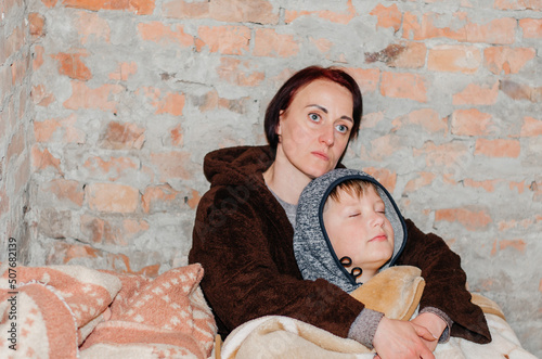 A mother and her son are hiding in the basement during an air raid photo