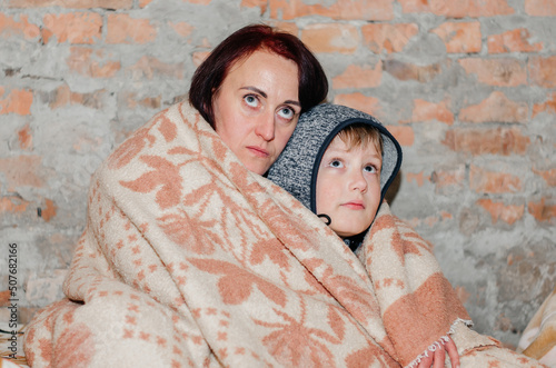 A mother and her son are hiding in the basement during an air raid photo