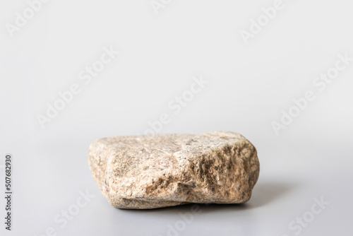 Natural stone stand for presentation and exhibitions on pastel gray background. Abstract podium for organic cosmetic products. Minimal style. Selective focus