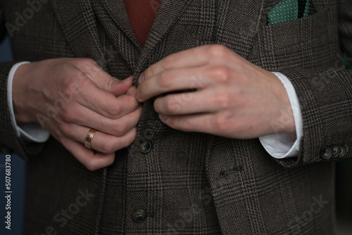 man fastening buttons on his vest
