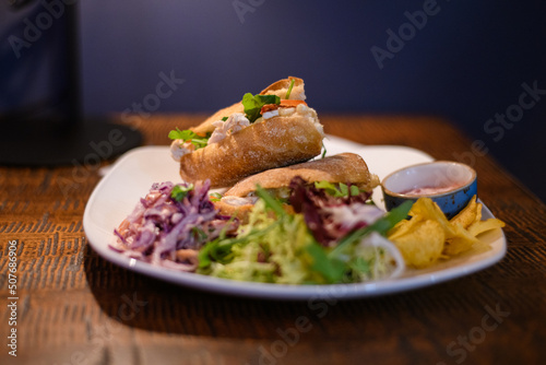 Close-up of chicken, brie and salad sandwiches with coleslaw, green salad and crisps photo