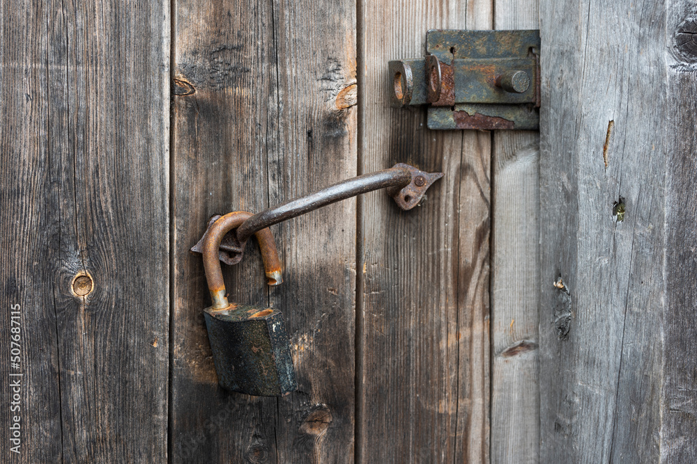 old rusty metal padlock on an old wooden door old rusty metal padlock on an old wooden door