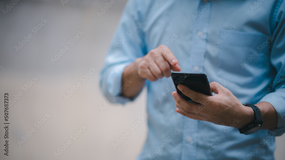 Close up on casual Man using smart phone, using mobile smart phone and online working on laptop computer at home office. Close up on casual Man using smart phone, using mobile smart phone and online working on laptop computer at home office.