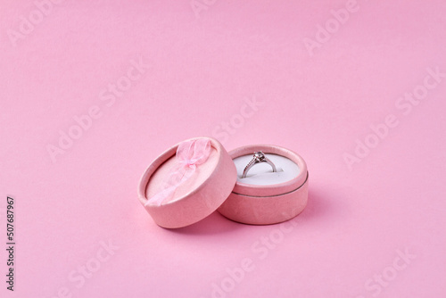Engagement ring in pink gift box on pink background. Romantic gift idea.